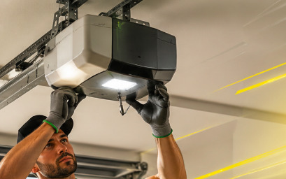 Technician working overhead on a garage door opener during an emergency call
